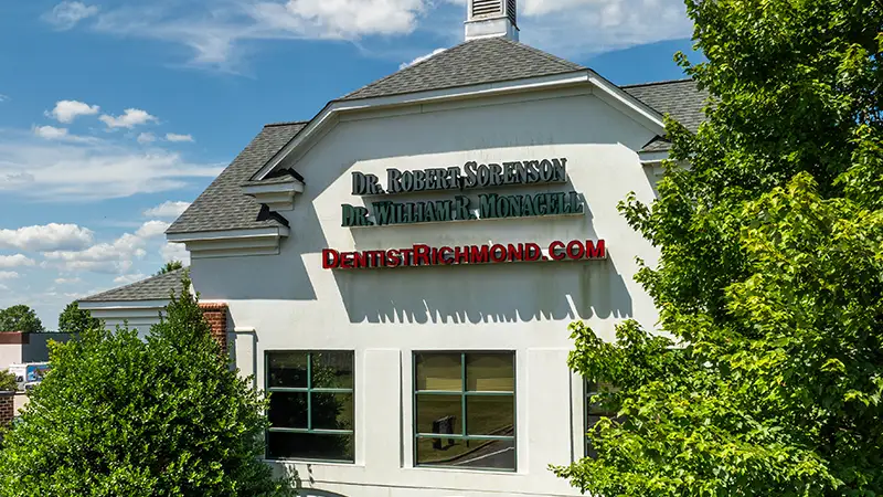 Exterior view of Midlothian Family Dentistry office building with signage on the front facade surrounded by green trees