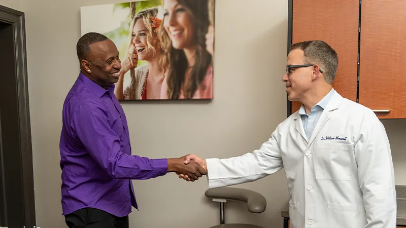Man shaking hands with a doctor in a medical office during a friendly consultation