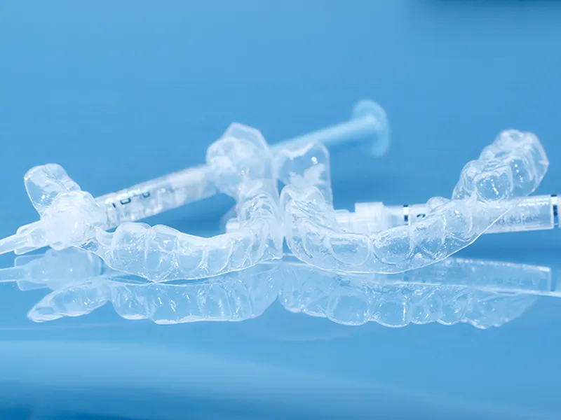 Close-up of custom clear PP dental trays with gel syringes