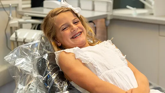 girl client wearing braces and smiling in dentist chair