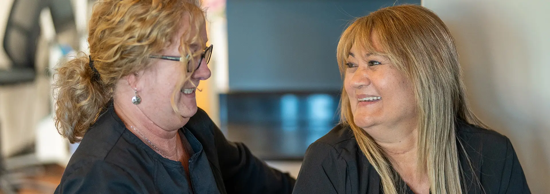 Two Dental Staff Members Smiling at Eachother