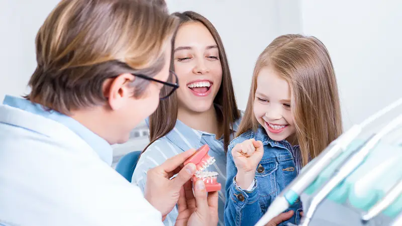 Dentist and mom making young patient comfortable through laughter