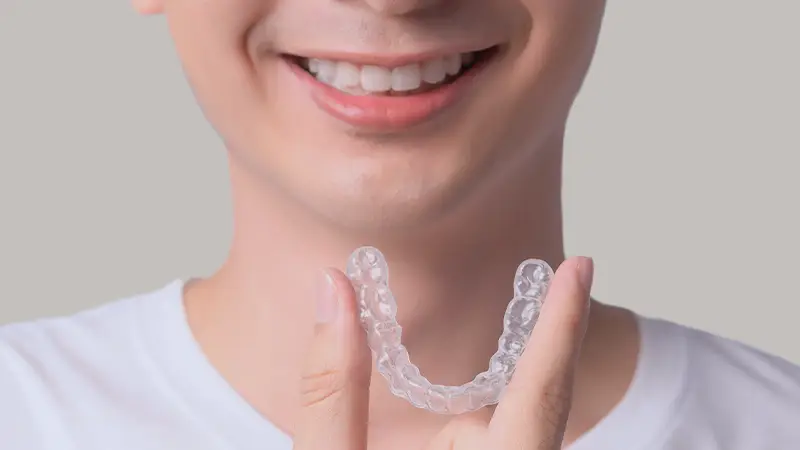 Patient holding invisalign smiling close up